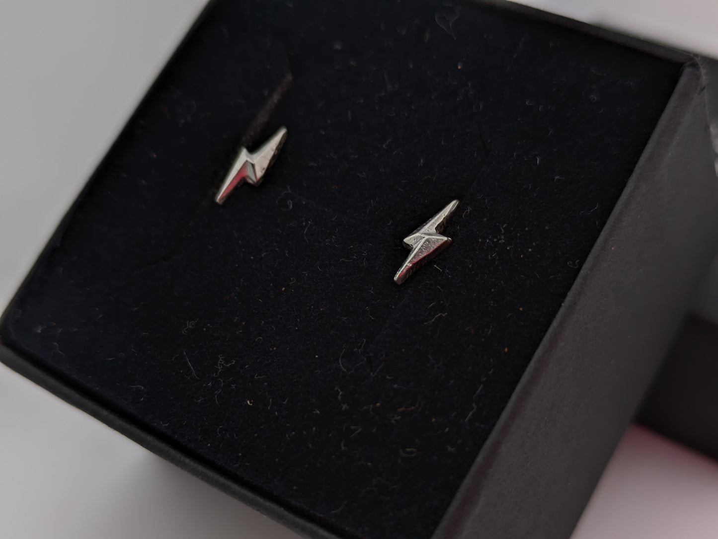 Silver lightning bolt earrings on a black jewelry box