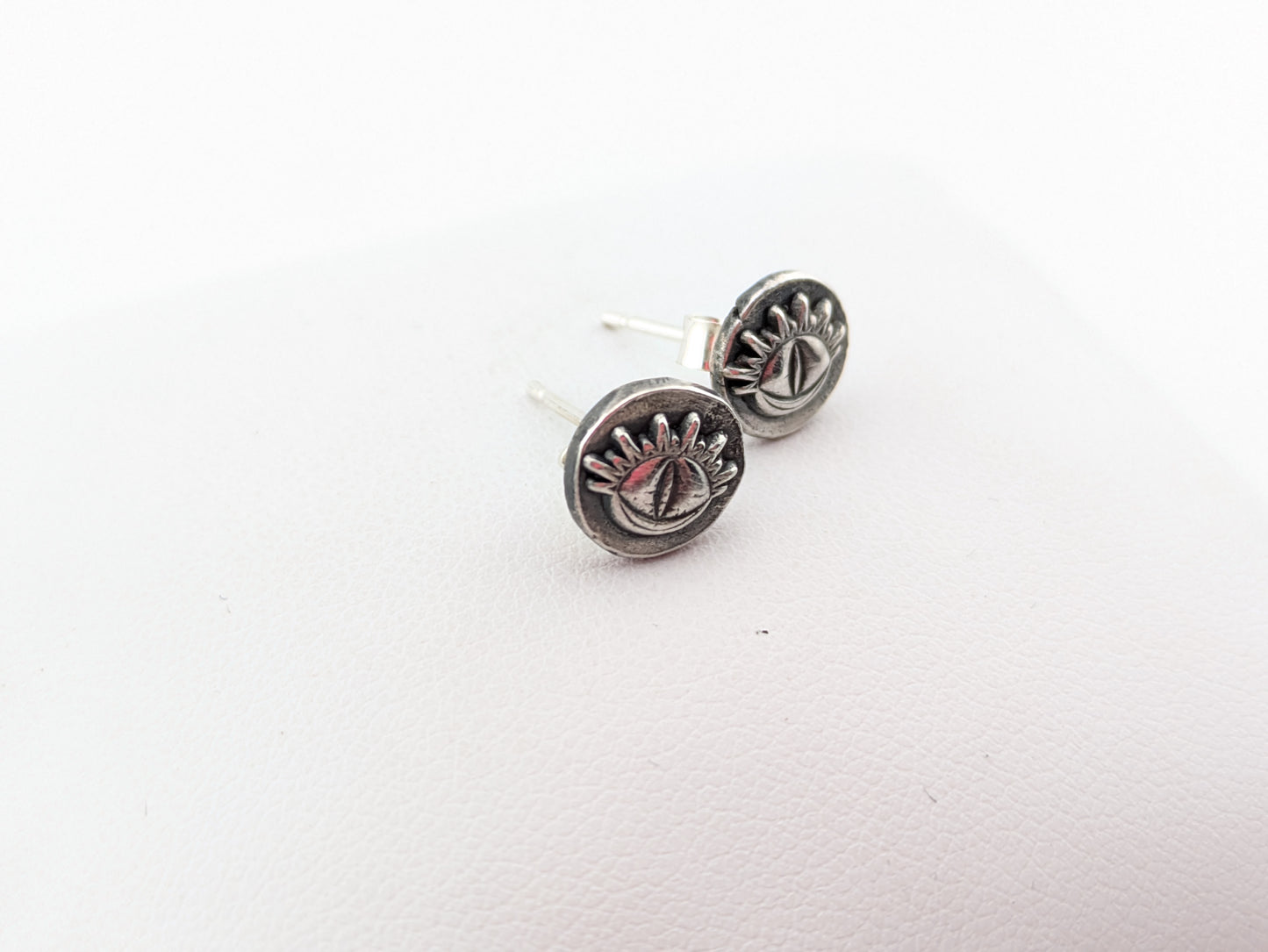 silver eye earrings on white background